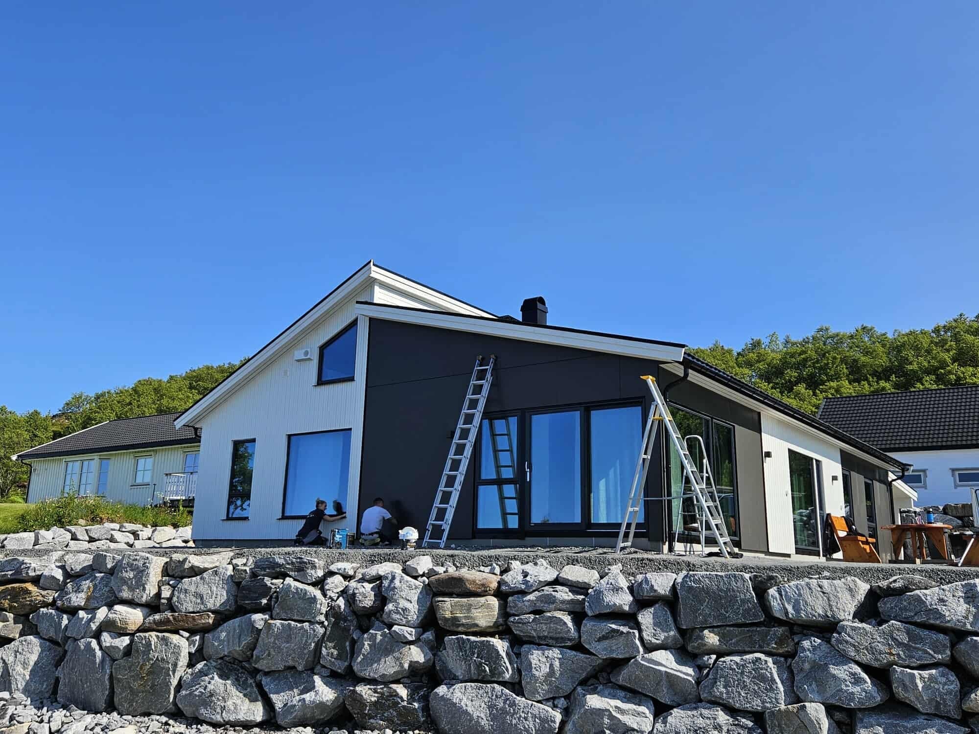 Nybygd enebolig på steinmur under blå himmel