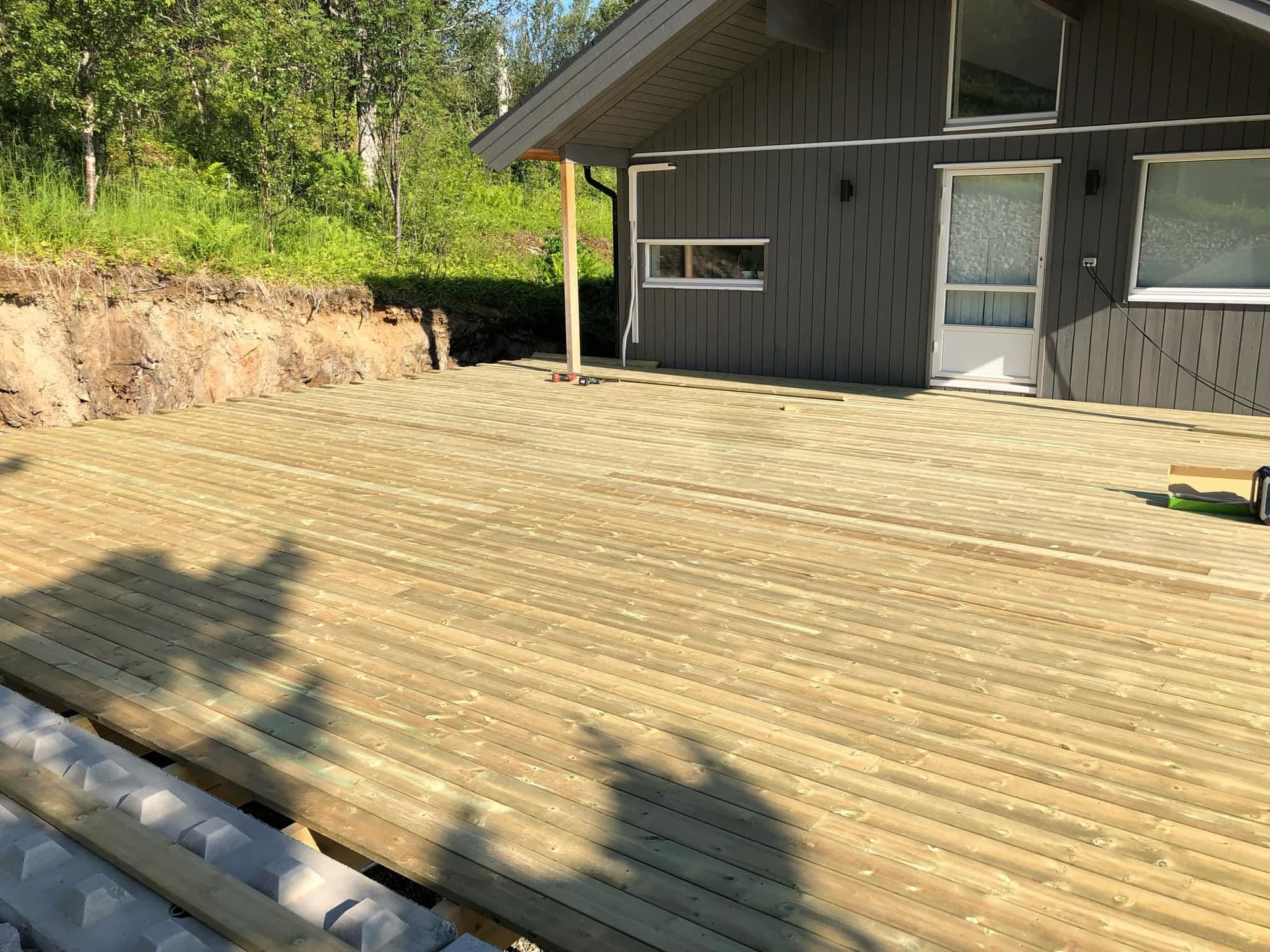 Ferdig terrasse i tre ved mørk bolig