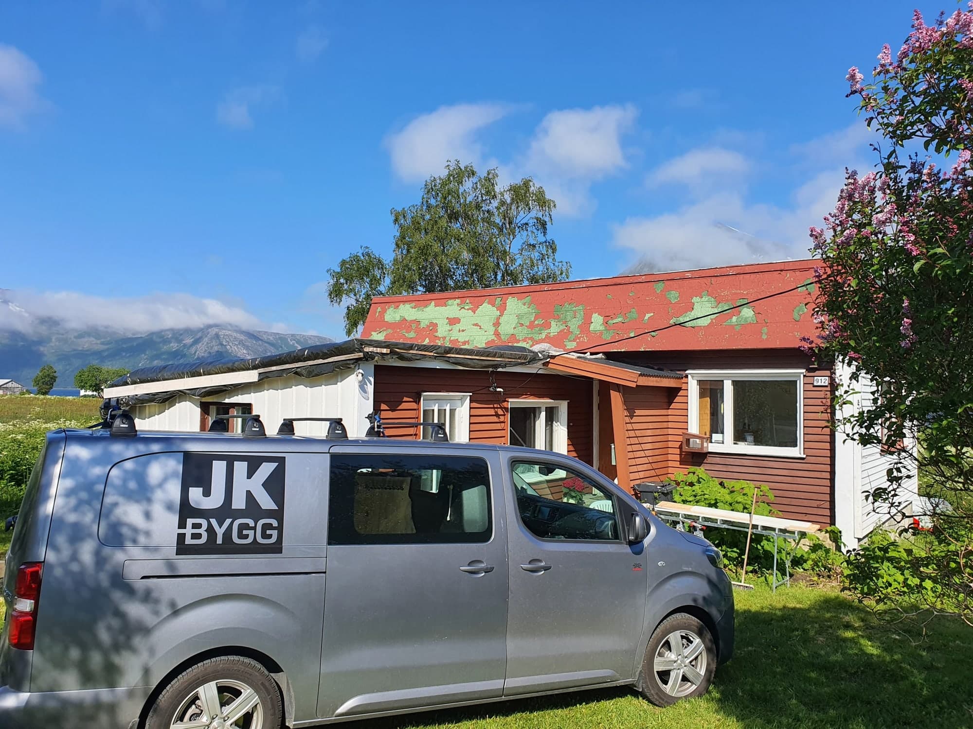 Firmabilen til JK Bygg foran et rødt hus